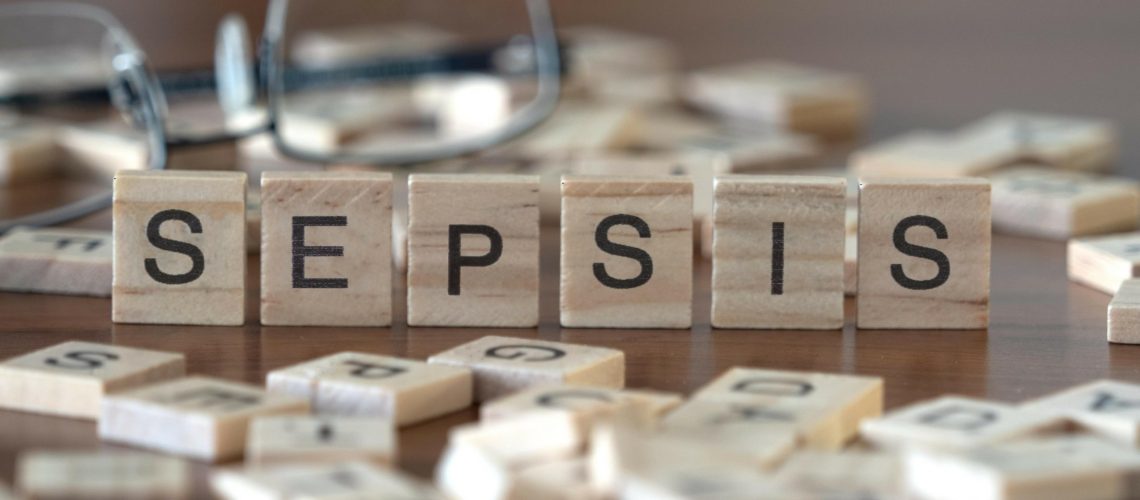 sepsis concept represented by wooden letter tiles on a wooden table with glasses and a book